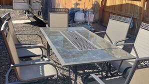 Un véhicule récréatif doté d’une porte coulissante, d’une table avec des chaises et, au fond, d’une clôture en bois.