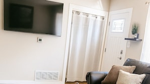 A living room with a wooden coffee table, a leather sofa, and a television mounted on the wall. - Applewood Charming Two Bedroom Big Fenced Yard (Fort Collins)