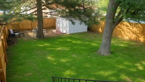 A backyard with a fenced area, a small shed, a tree, and a seating area with a table and chairs. - Applewood Charming Two Bedroom Big Fenced Yard (Fort Collins)