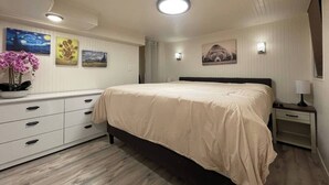 A bedroom with a bed, bedside tables, a dresser, and wall-mounted artwork.