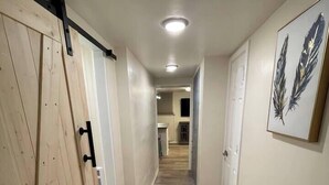 A hallway with wooden flooring, white walls, and a ceiling light.