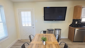 Una cocina moderna con una mesa de comedor de madera, sillas, un televisor de pantalla plana y electrodomésticos integrados.