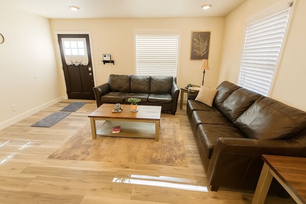 A living room with a brown leather sofa, a wooden coffee table, and a patterned rug.