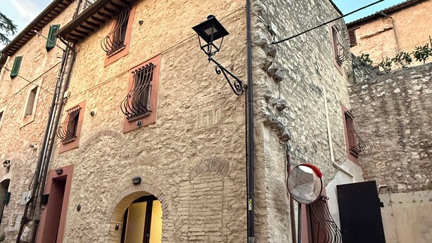 A traditional stone building with a yellow door, a small balcony, and a street lamp. - Casa MaNà Trevi, your Country Chic retreat for a dolce far niente in Umbria (Trevi)