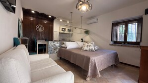 A modern bedroom with a bed, a sofa, a kitchenette, and a window with a view. - Casa MaNà Trevi, your Country Chic retreat for a dolce far niente in Umbria (Trevi)