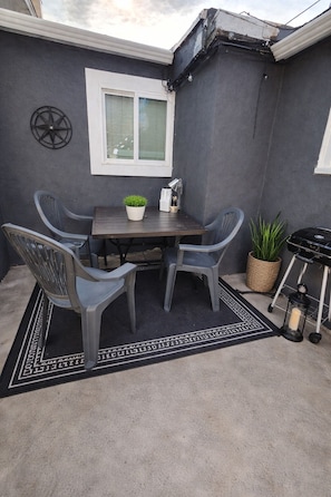 A patio with a table and four chairs, a potted plant, a grill, and a lantern. - Quiet Cozy Downtown Cheyenne (Cheyenne)