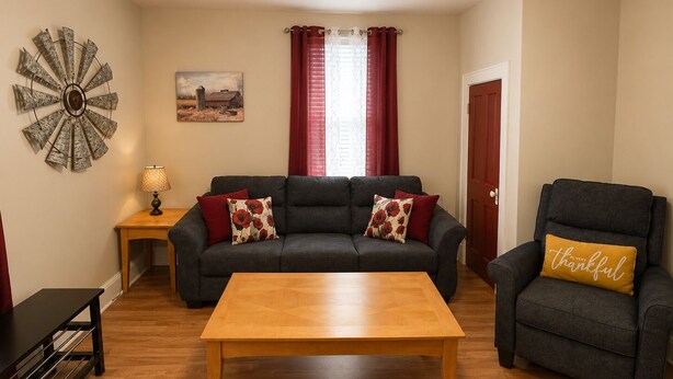 A living room with a sofa, armchair, wooden coffee table, and a side table with a lamp.