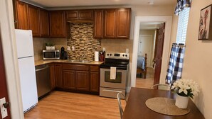 A kitchen with wooden cabinets, a microwave, stove, and a dining table with chairs. - Farm Charm in Downtown Cheyenne (Cheyenne)