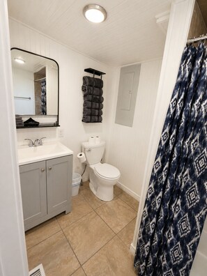 A bathroom with a toilet, sink, and towel rack. - Farm Charm in Downtown Cheyenne (Cheyenne)