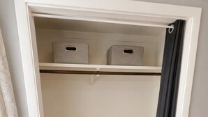 A closet with two storage boxes, a hanging rod, and a partially drawn curtain.