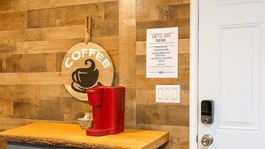 A kitchenette with a wooden wall, a coffee sign, a red coffee machine, and two stools. - Cottage Studio Cheyenne (Cheyenne)