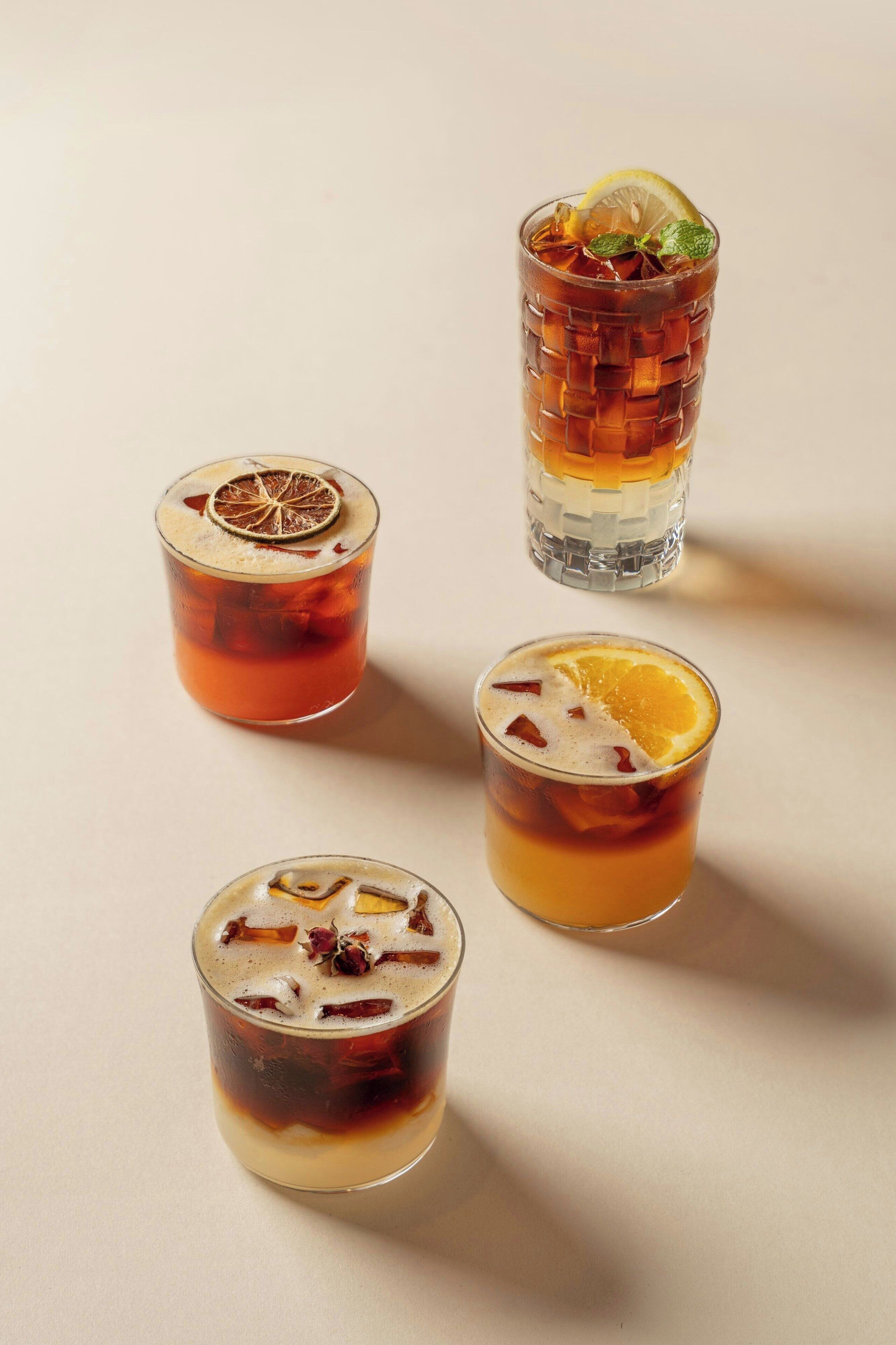 Quatre verres de thé glacé, chacun agrémenté d’une garniture différente.