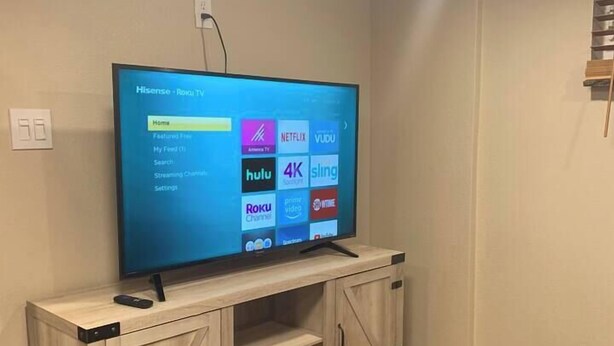 Un téléviseur à écran plat fixé sur un meuble télé en bois, avec un câble qui y est raccordé.