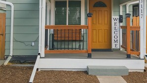 A small, single-story house with a welcoming front porch, a wooden bench, and a 'WELCOME' sign. - Cozy cottage in Cheyenne (Cheyenne)