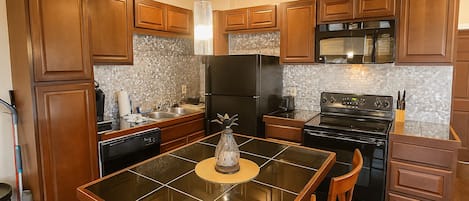 A kitchen with wooden cabinets, a black refrigerator, a stove, and a dining table with chairs.