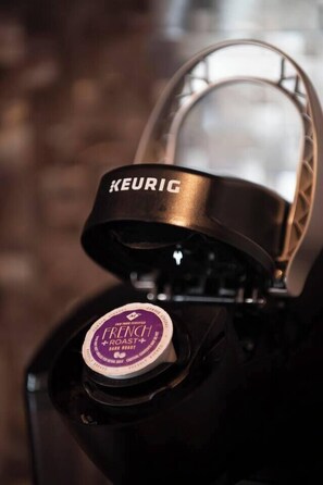 A coffee machine with a "KEURIG" brand label and a "FRENCH ROAST" coffee pod.