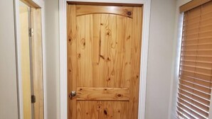 A wooden door with a white frame, a window with blinds, and a wooden floor. - Cheyenne Frontier Apartment (Cheyenne)