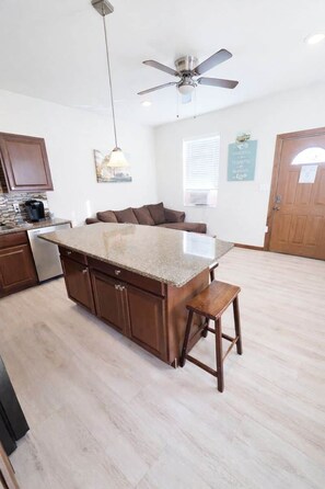 A kitchen with a central island, wooden cabinets, a ceiling fan, and a coffee maker. - Cheyenne Frontier Homes #2 (Cheyenne)