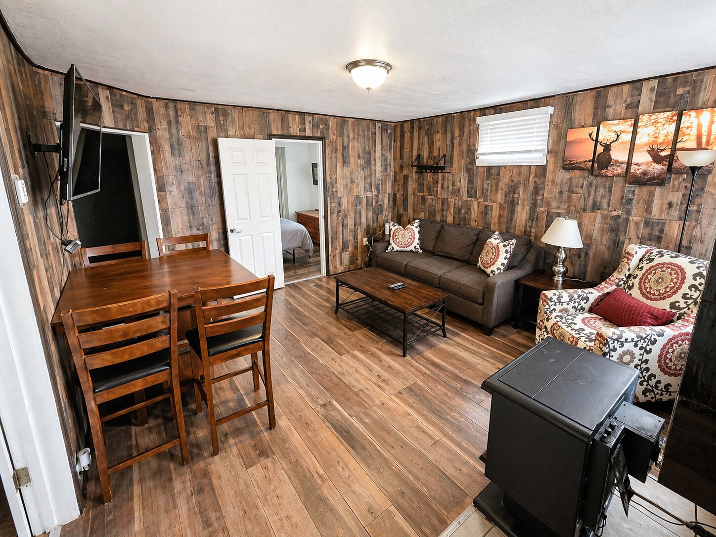 Un salon avec un plancher en bois, un canapé, une table basse et un téléviseur.