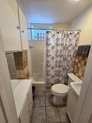 Ein kleines Badezimmer mit Toilette, Duschvorhang und Handtuchhalter.