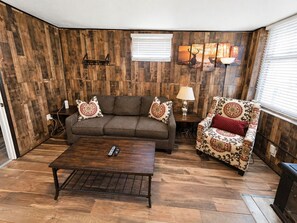 Un salon avec un canapé marron, un fauteuil à motifs et une table basse.