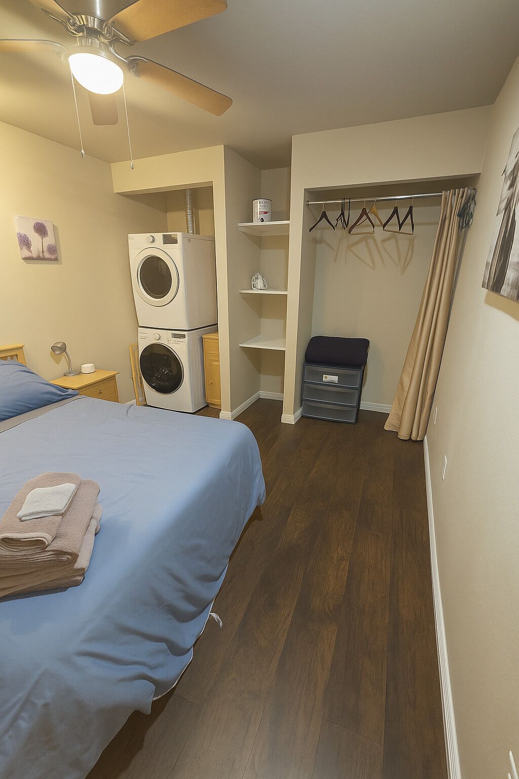A bedroom with a bed, a washing machine, a wardrobe, and a ceiling fan.