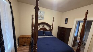 Un lit à baldaquin avec une tête de lit en bois, une table de chevet en bois et une commode.