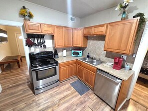 A kitchen with wooden cabinets, a stainless steel stove, a microwave, and a dishwasher. - Downtown Cheyenne Duplex (Cheyenne)