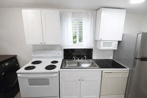 A compact kitchen with white cabinets, a stove, a sink, and a dishwasher.