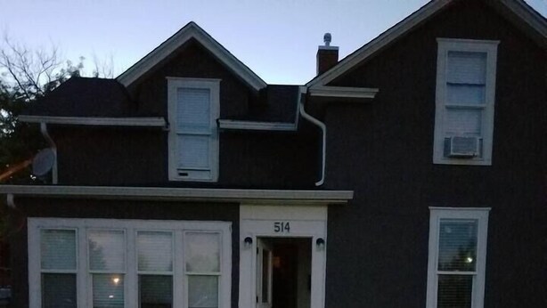 Una casa de dos pisos con el número 514 en la puerta principal, un camino que lleva a la entrada y una cerca de madera a cada lado.