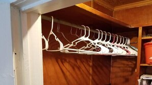Un armario de madera con varios estantes y una barra para colgar.