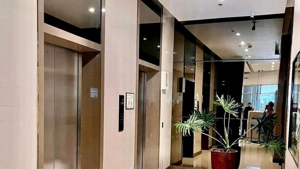 Un moderno vestíbulo de hotel con suelo de baldosas, ascensores y una gran planta en maceta.