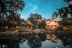 Une cour paisible avec un bassin aux eaux calmes, une architecture traditionnelle et une végétation luxuriante.