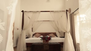 A bedroom with a four-poster bed, a ceiling fan, and a window with natural light.
