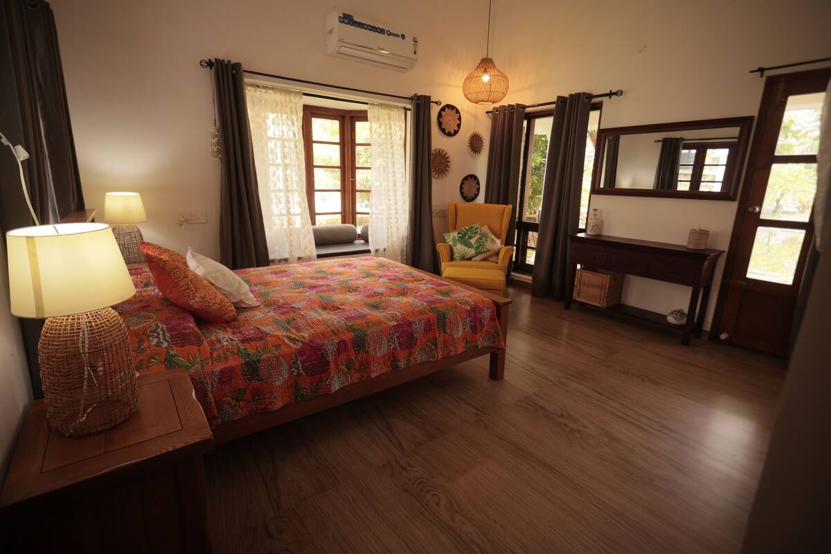 A bedroom with a bed, a chair, a desk, and a window.