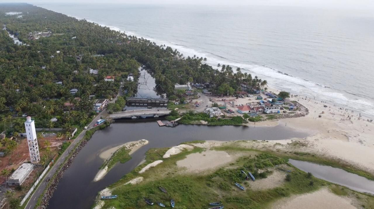 An aerial view of a coastal area with a beach, a river, and a temple-like structure.