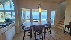 A dining area with a table and four chairs, a staircase, and a view of the water. - Waterfront 5BR/5.5BA Home w/ 2 Docks and Private pool and spa (Montgomery)