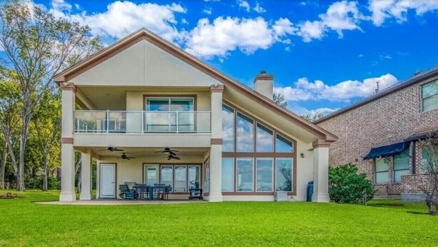 A two-story house with a balcony, large windows, and a well-maintained lawn. - Waterfront 5BR/5.5BA Home w/ 2 Docks and Private pool and spa (Montgomery)