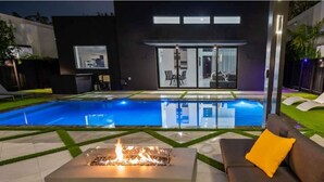 A modern outdoor pool area with a fire feature and a sofa.