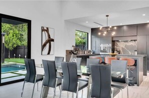 Une cuisine moderne avec un coin repas, de grandes fenêtres et une vue sur une piscine.