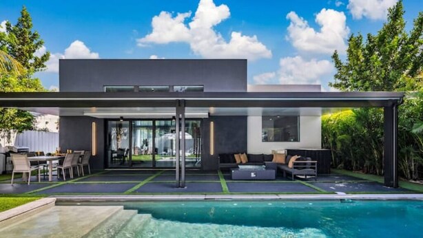 Ein modernes Haus mit Swimmingpool, Sitzgelegenheit im Freien und einer überdachten Terrasse.