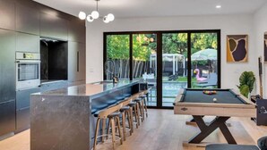 Una cocina moderna con barra, mesa de billar y vistas al exterior.