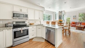 A modern kitchen with white cabinetry, stainless steel appliances, and a granite countertop. - Bright & Cozy Getaway (Park City)