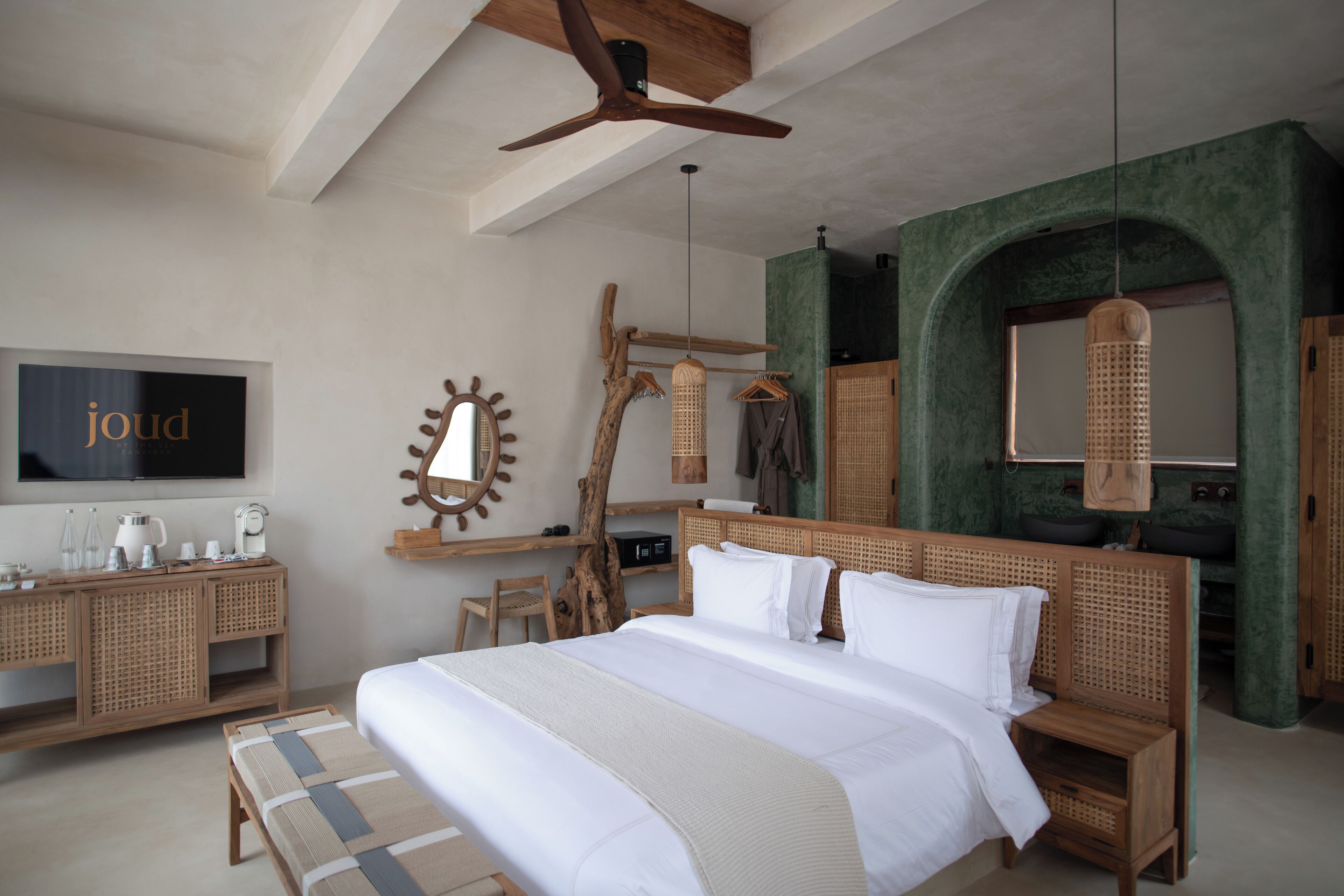 A spacious bedroom with a large bed, wooden headboard, and a television on the wall.