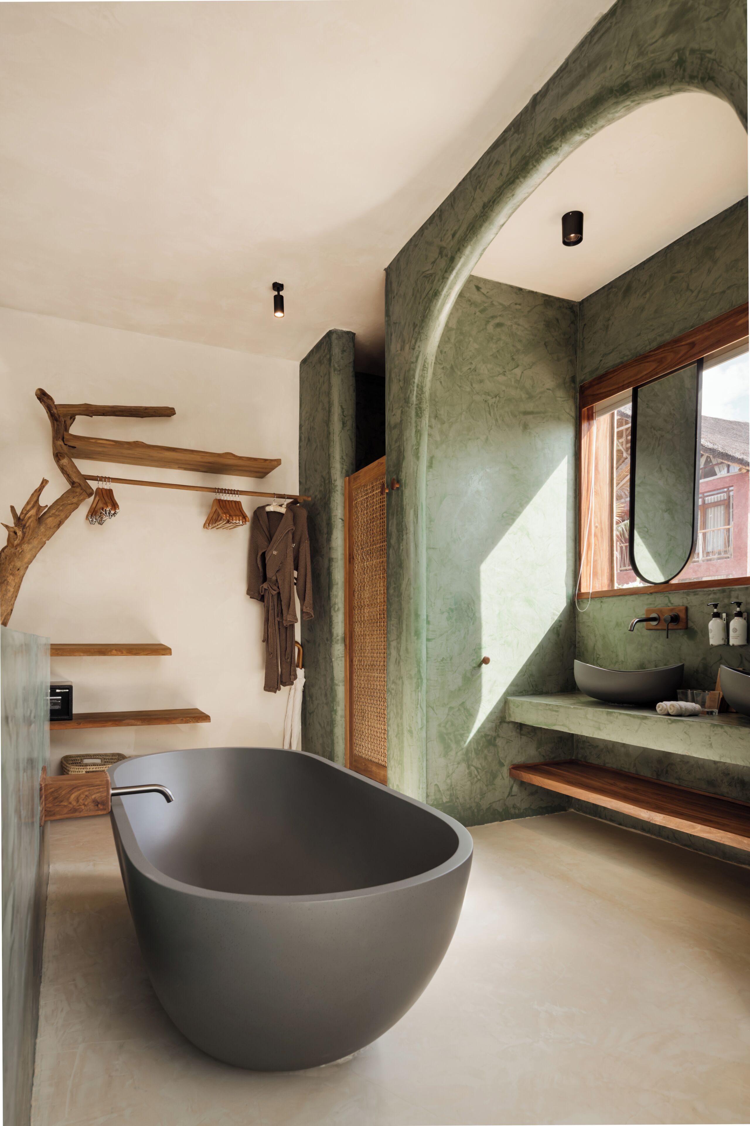 A modern bathroom with a large freestanding bathtub, wooden shelves, and a mirror.