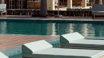 Una piscina al aire libre, sombrillas, sillones reclinables de piscina