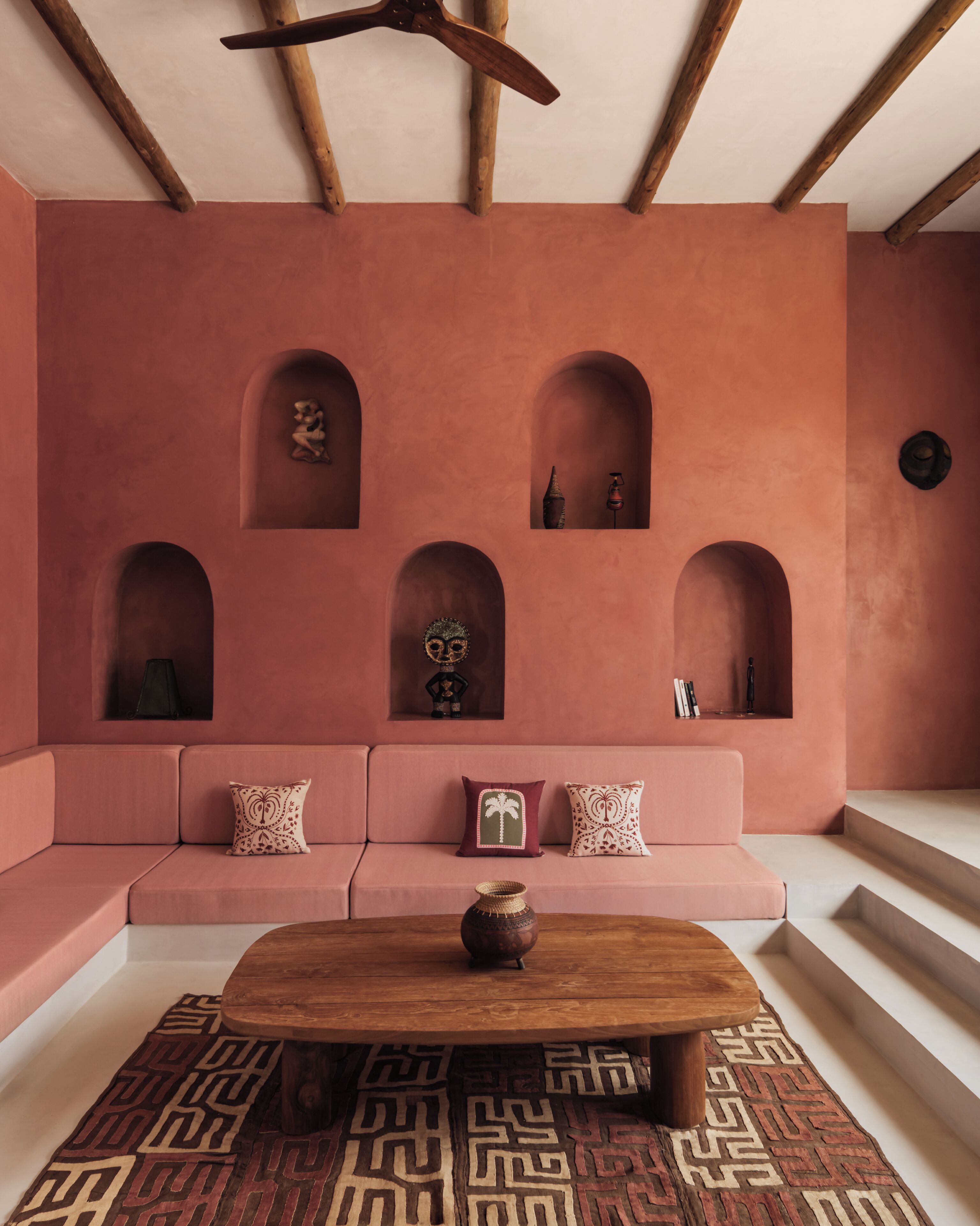 A room with a pink sofa, a wooden coffee table, and a patterned rug.