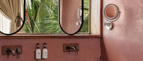 A bathroom with two vessel sinks, a large mirror, and a window with a view of greenery.