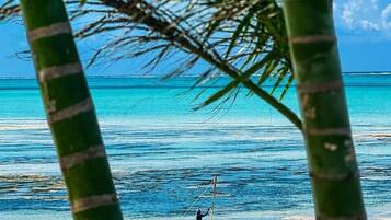 Na praia, areia branca, espreguiçadeiras, guarda-sóis