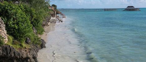 A beach with a wooden walkway leading to a pier.